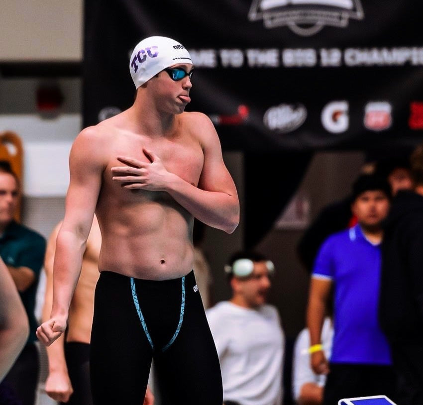 Charlie Bishop, Texas Christian University swimmer, standing poolside in racing gear during a swim meet