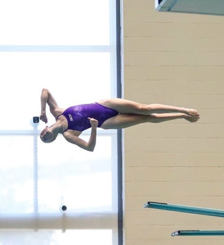 Hailey-Cate Bull, Grand Canyon University diver, mid-dive off the board in a purple swimsuit